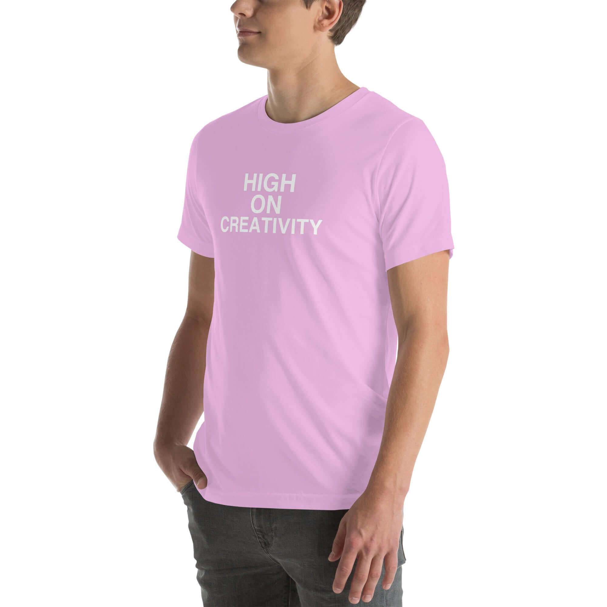 Man wearing a lilac t-shirt with white text ‘HIGH ON CREATIVITY’, standing sideways with one hand in pocket