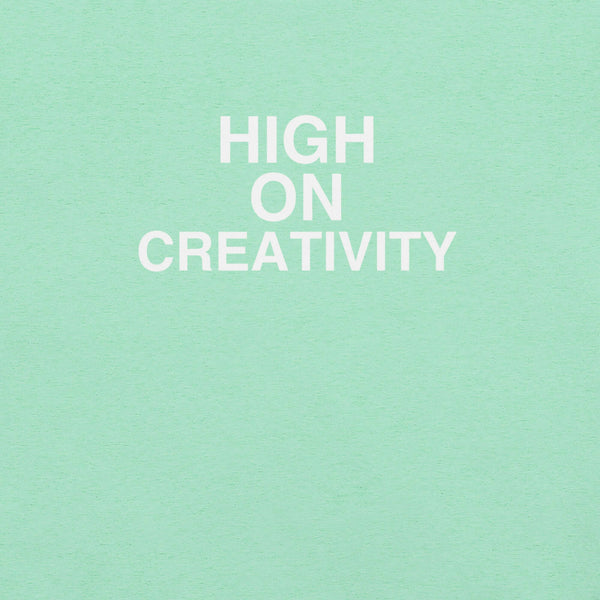 Close-up of mint t-shirt fabric with the phrase “HIGH ON CREATIVITY” printed in bold white uppercase letters in three lines.