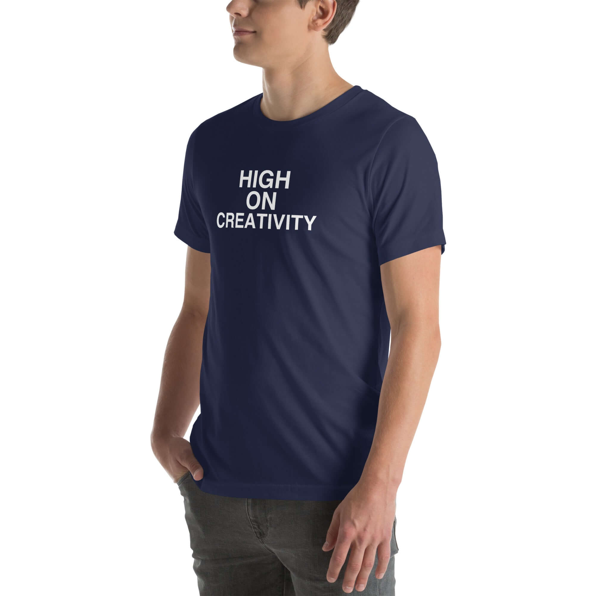 Man wearing a navy t-shirt with white text ‘HIGH ON CREATIVITY’, standing sideways with one hand in pocket
