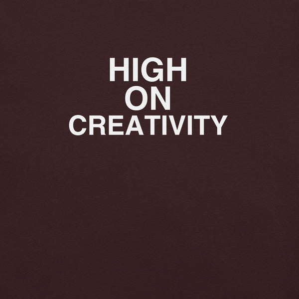 Close-up of oxblood black t-shirt fabric with the phrase “HIGH ON CREATIVITY” printed in bold white uppercase letters in three lines.