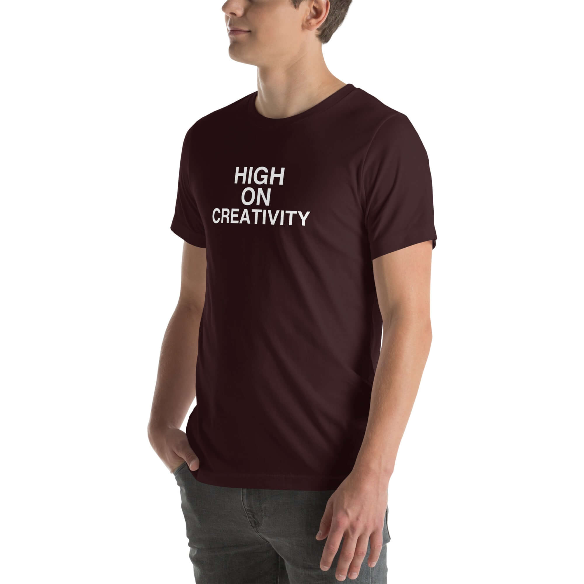 Man wearing a oxblood black  t-shirt with white text ‘HIGH ON CREATIVITY’, standing sideways with one hand in pocket