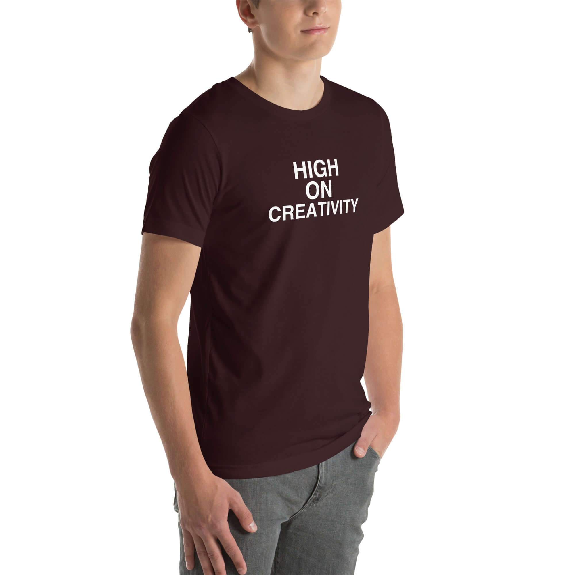 Young man wearing a oxblood black t-shirt with white text ‘HIGH ON CREATIVITY’, standing angled to the side with hands in pockets.