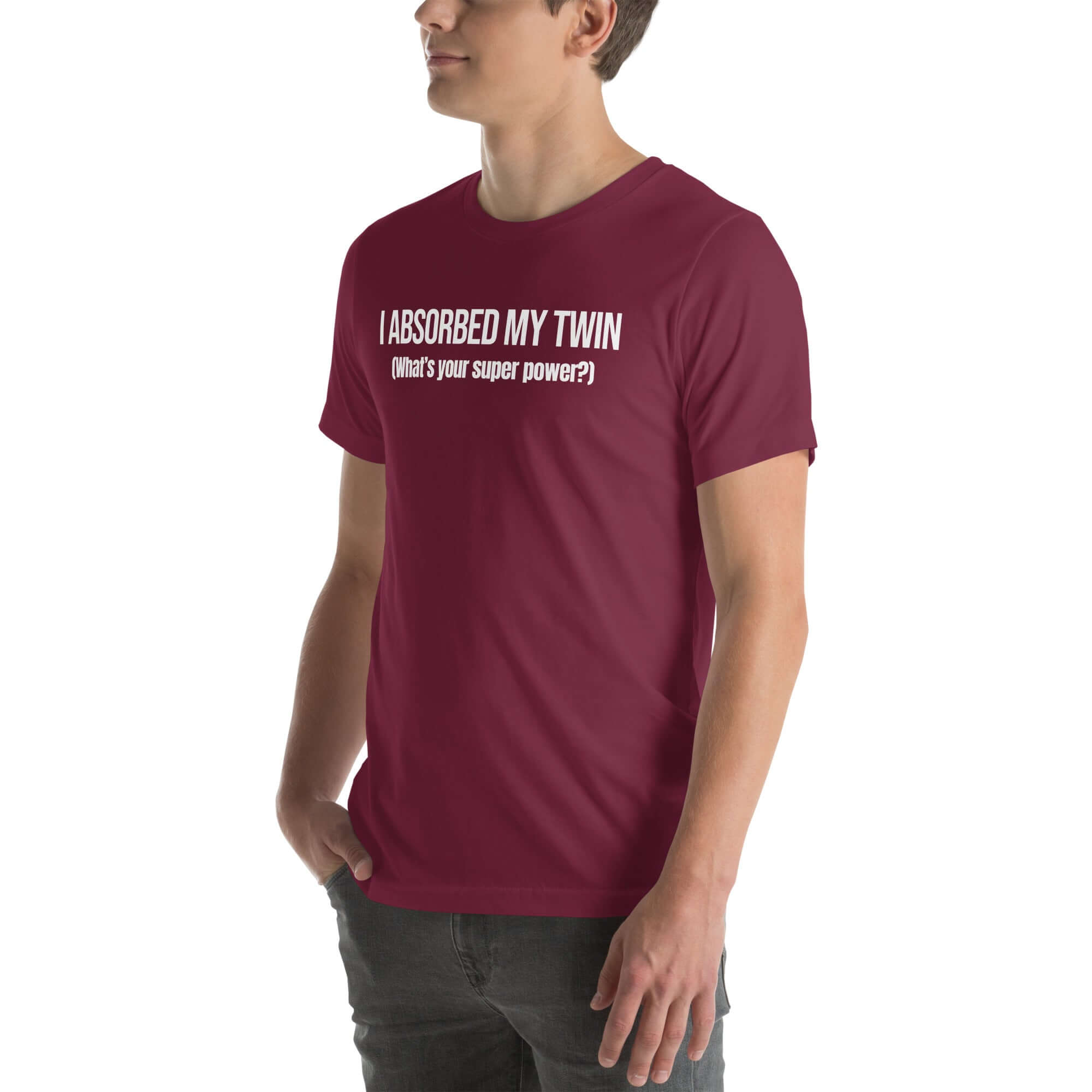 Man wearing maroon “I ABSORBED MY TWIN (What’s your super power?)” t-shirt, standing sideways with hands in pockets.