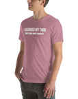 Man wearing orchid “I ABSORBED MY TWIN (What’s your super power?)” t-shirt, standing sideways with hands in pockets.