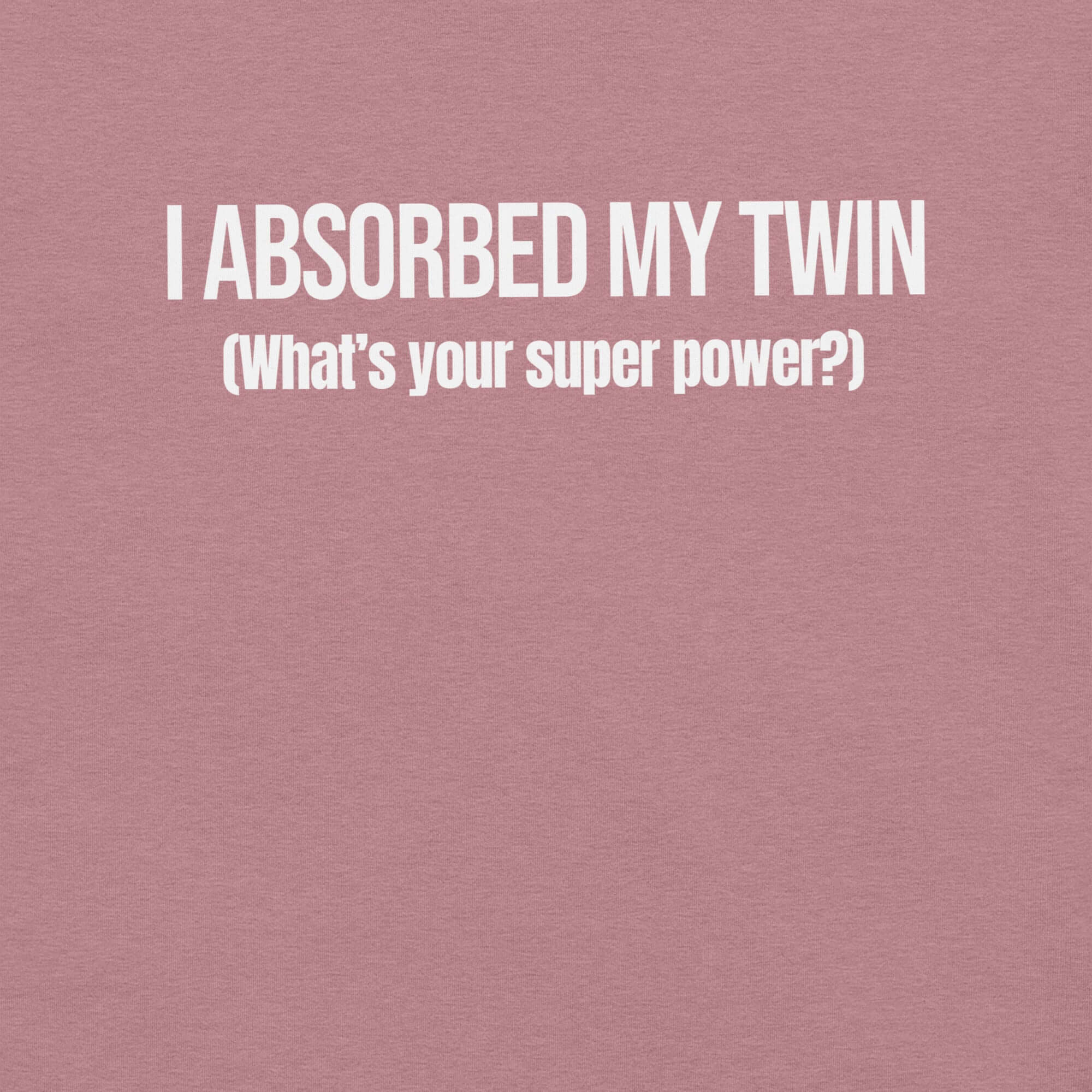 Close-up of orchid t-shirt with white text “I ABSORBED MY TWIN (What’s your super power?)” printed on the front.