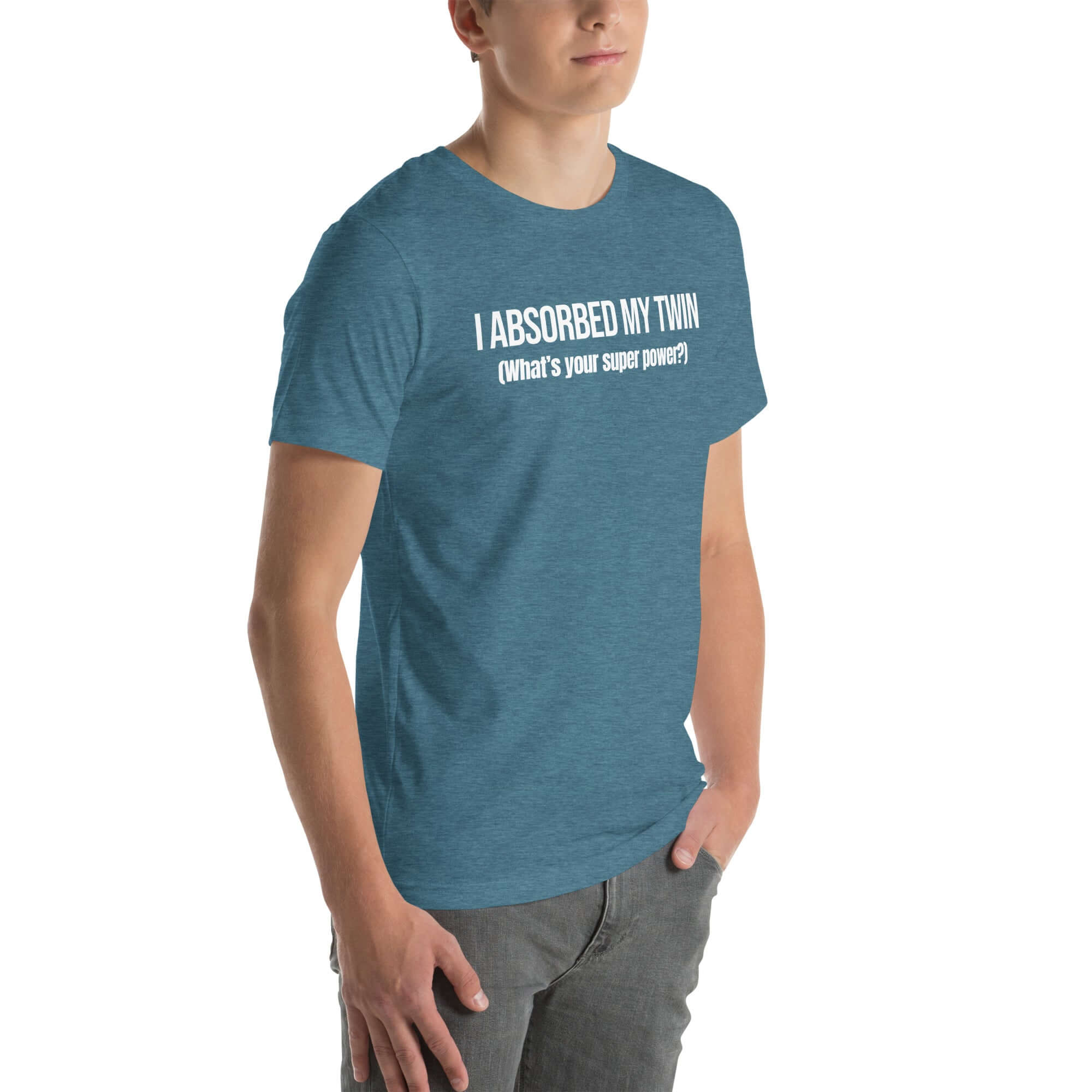 Man wearing teal “I ABSORBED MY TWIN (What’s your super power?)” t-shirt, standing angled to the side with hands in pockets.