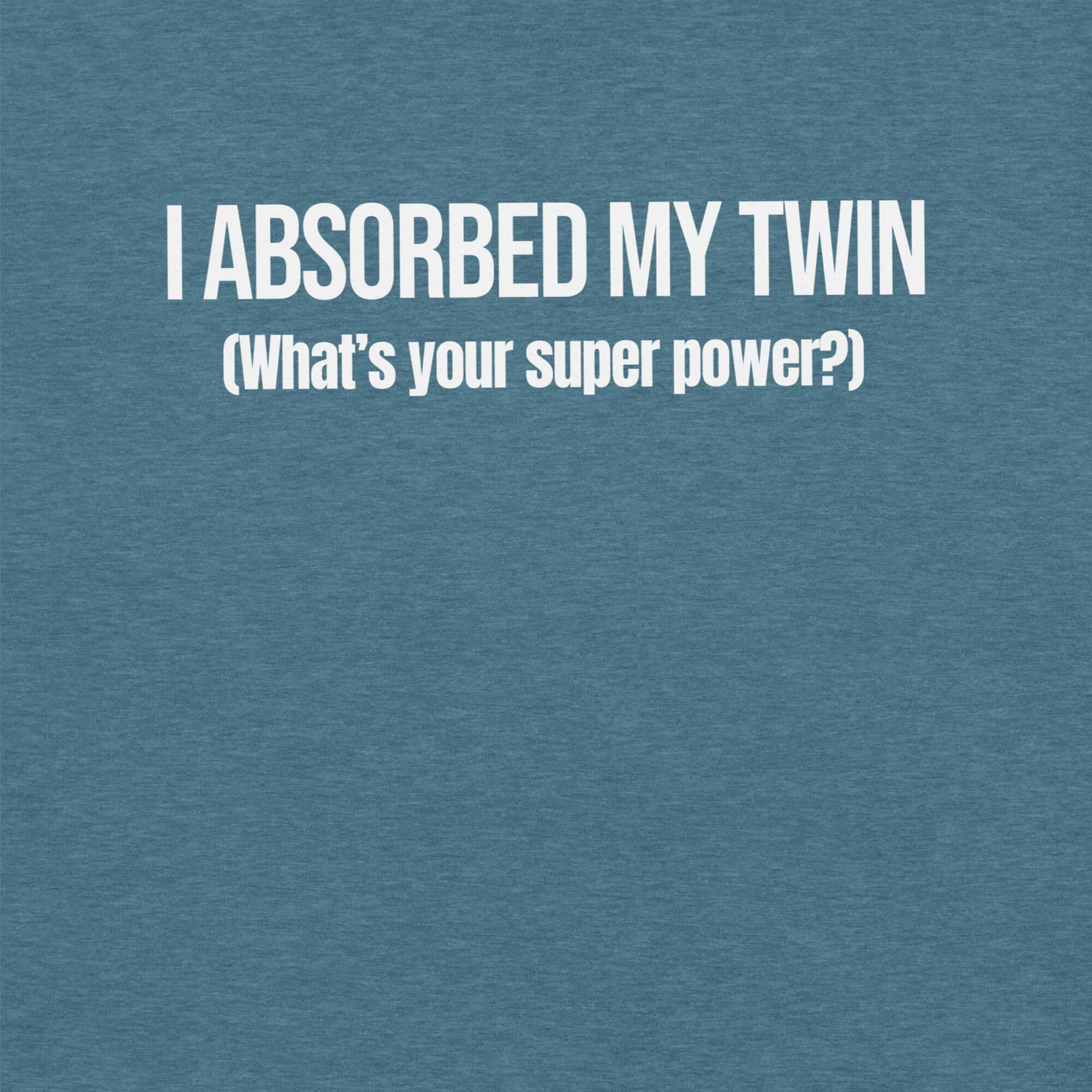 Close-up of teal t-shirt with white text “I ABSORBED MY TWIN (What’s your super power?)” printed on the front.