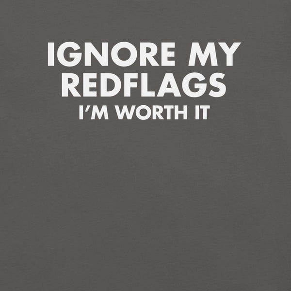 Close-up of asphalt t-shirt with bold white text “IGNORE MY RED FLAGS I’M WORTH IT” printed on the front.        