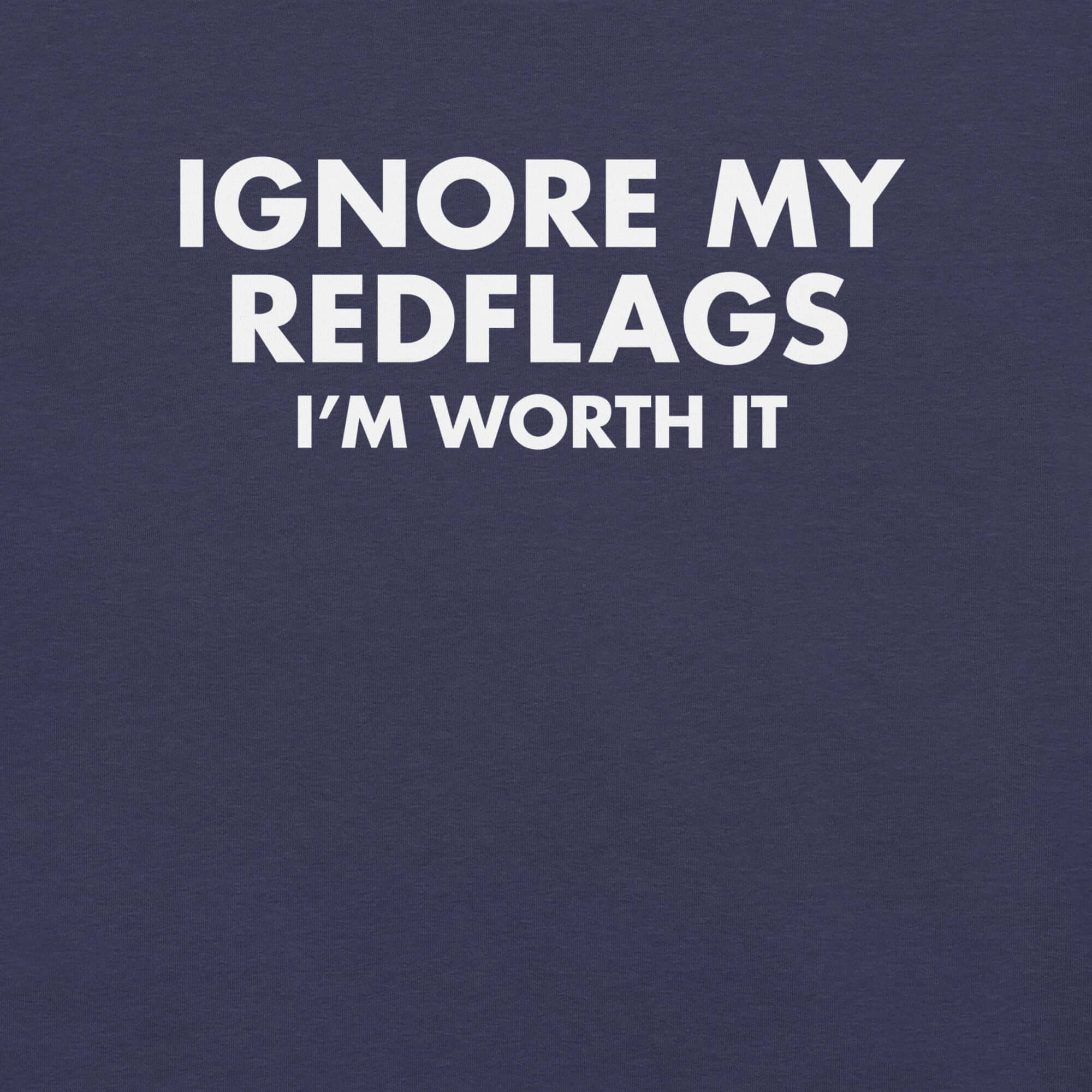 Close-up of navy t-shirt with bold white text “IGNORE MY RED FLAGS I’M WORTH IT” printed on the front.        