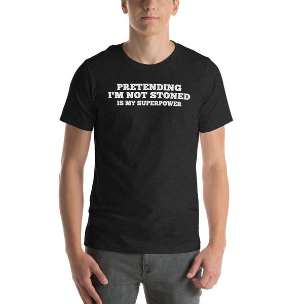 Man wearing black “PRETENDING I’M NOT STONED IS MY SUPERPOWER” t-shirt, standing casually with hands by pockets.