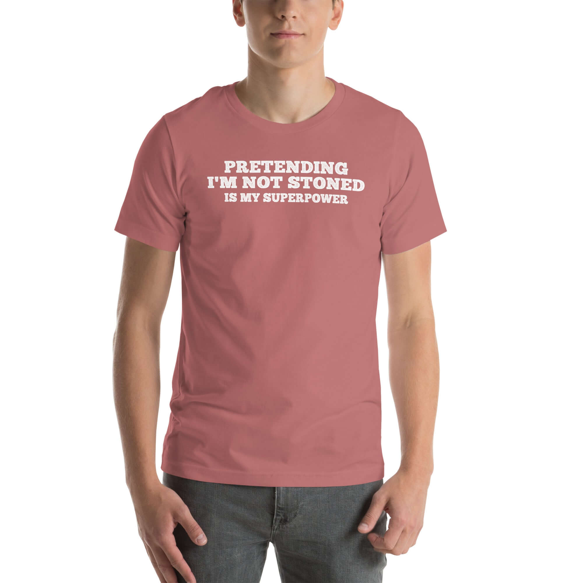 Man wearing mauve “PRETENDING I’M NOT STONED IS MY SUPERPOWER” t-shirt, standing casually with hands by pockets.
