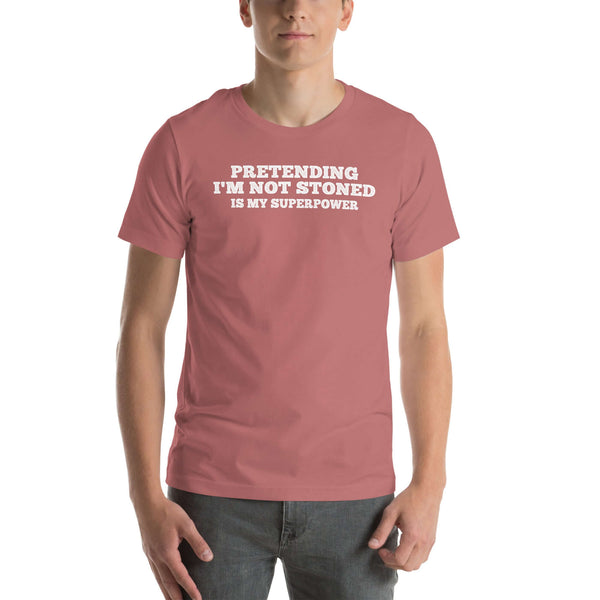 Man wearing mauve “PRETENDING I’M NOT STONED IS MY SUPERPOWER” t-shirt, standing casually with hands by pockets.