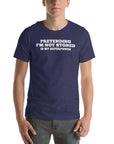 Man wearing navy “PRETENDING I’M NOT STONED IS MY SUPERPOWER” t-shirt, standing casually with hands by pockets.