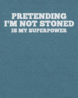 Close-up of teal t-shirt with white text that says “PRETENDING I’M NOT STONED IS MY SUPERPOWER.”