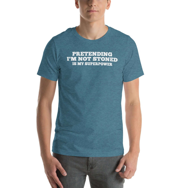 Man wearing teal “PRETENDING I’M NOT STONED IS MY SUPERPOWER” t-shirt, standing casually with hands by pockets.