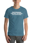 Man wearing teal “PRETENDING I’M NOT STONED IS MY SUPERPOWER” t-shirt, standing casually with hands by pockets.
