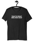 Black “THAT’S WHAT SHE/HER SAID” t-shirt hanging on a hanger, front design visible.      