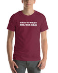 Man wearing maroon “THAT’S WHAT SHE/HER SAID” t-shirt, hands in pockets, looking relaxed to the front