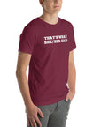 Man wearing maroon “THAT’S WHAT SHE/HER SAID” t-shirt, standing casually with one hand in pocket, looking slightly to the side