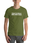 Man wearing olive “THAT’S WHAT SHE/HER SAID” t-shirt, hands in pockets, looking relaxed to the front