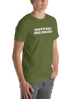 Man wearing olive “THAT’S WHAT SHE/HER SAID” t-shirt, standing casually with one hand in pocket, looking slightly to the side