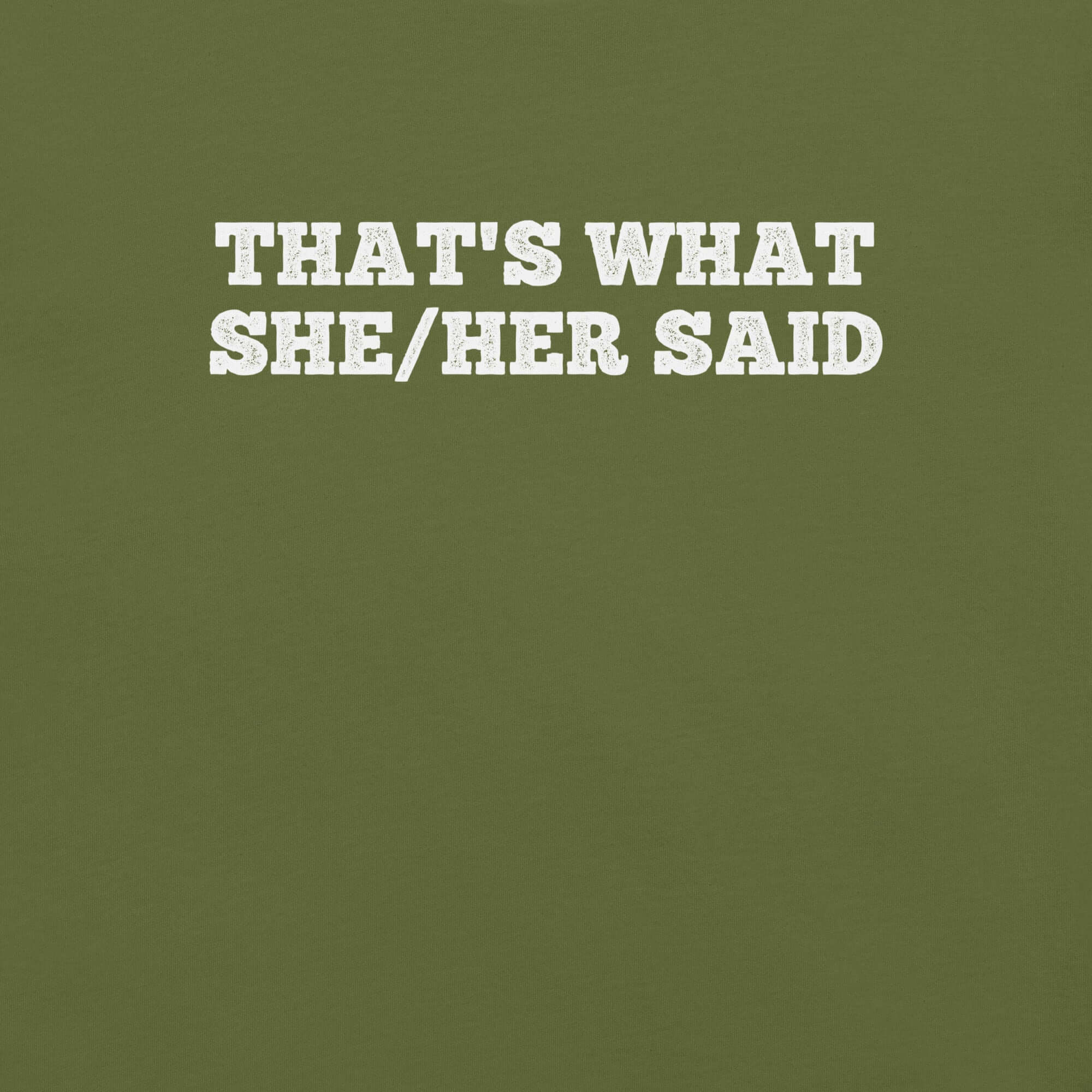Close-up of olive t-shirt with bold white text “THAT’S WHAT SHE/HER SAID” across the chest
