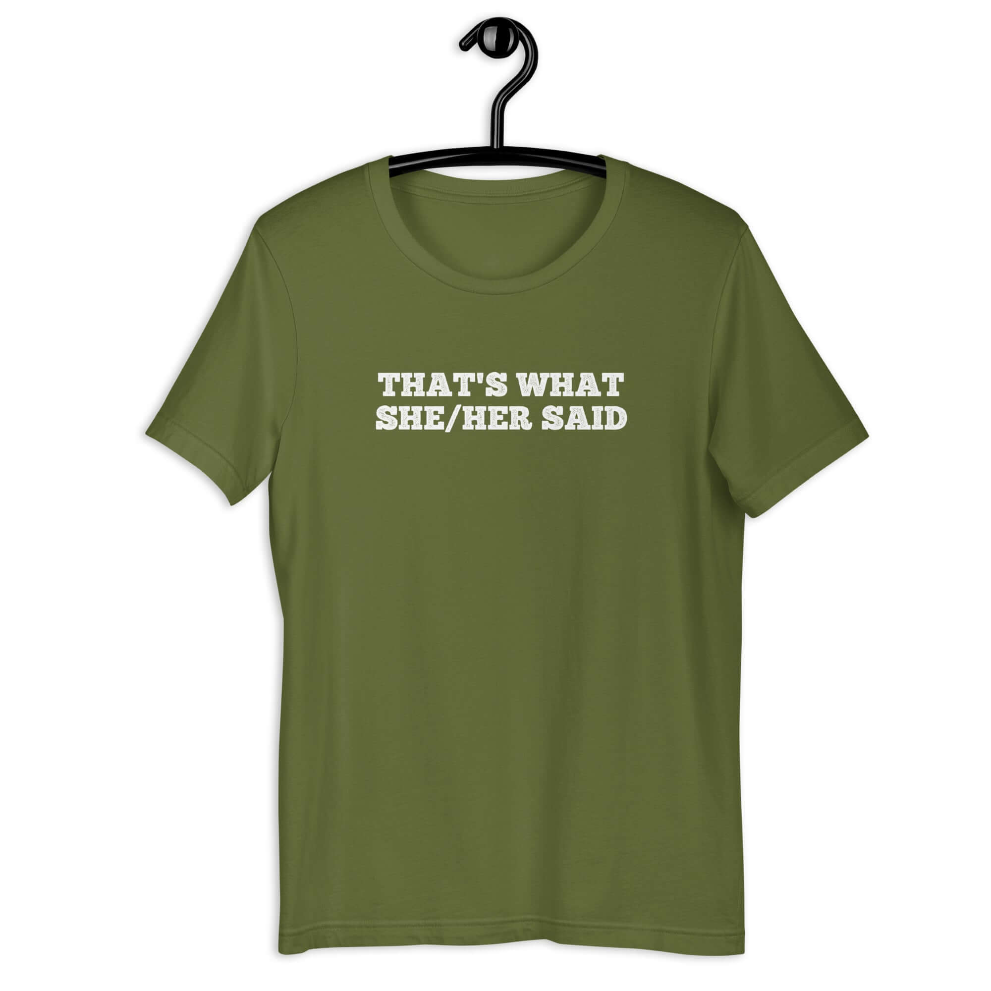 Olive “THAT’S WHAT SHE/HER SAID” t-shirt hanging on a hanger, front design visible.      