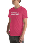 Man wearing a pink “THAT’S WHAT SHE/HER SAID” t-shirt, standing with hands in pockets, looking to the side.