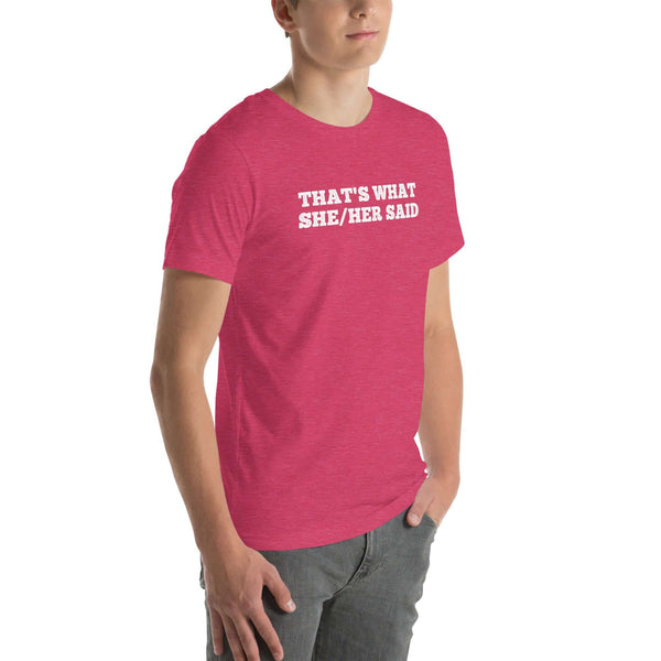 Man wearing pink “THAT’S WHAT SHE/HER SAID” t-shirt, standing casually with one hand in pocket, looking slightly to the side