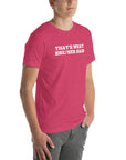 Man wearing pink “THAT’S WHAT SHE/HER SAID” t-shirt, standing casually with one hand in pocket, looking slightly to the side