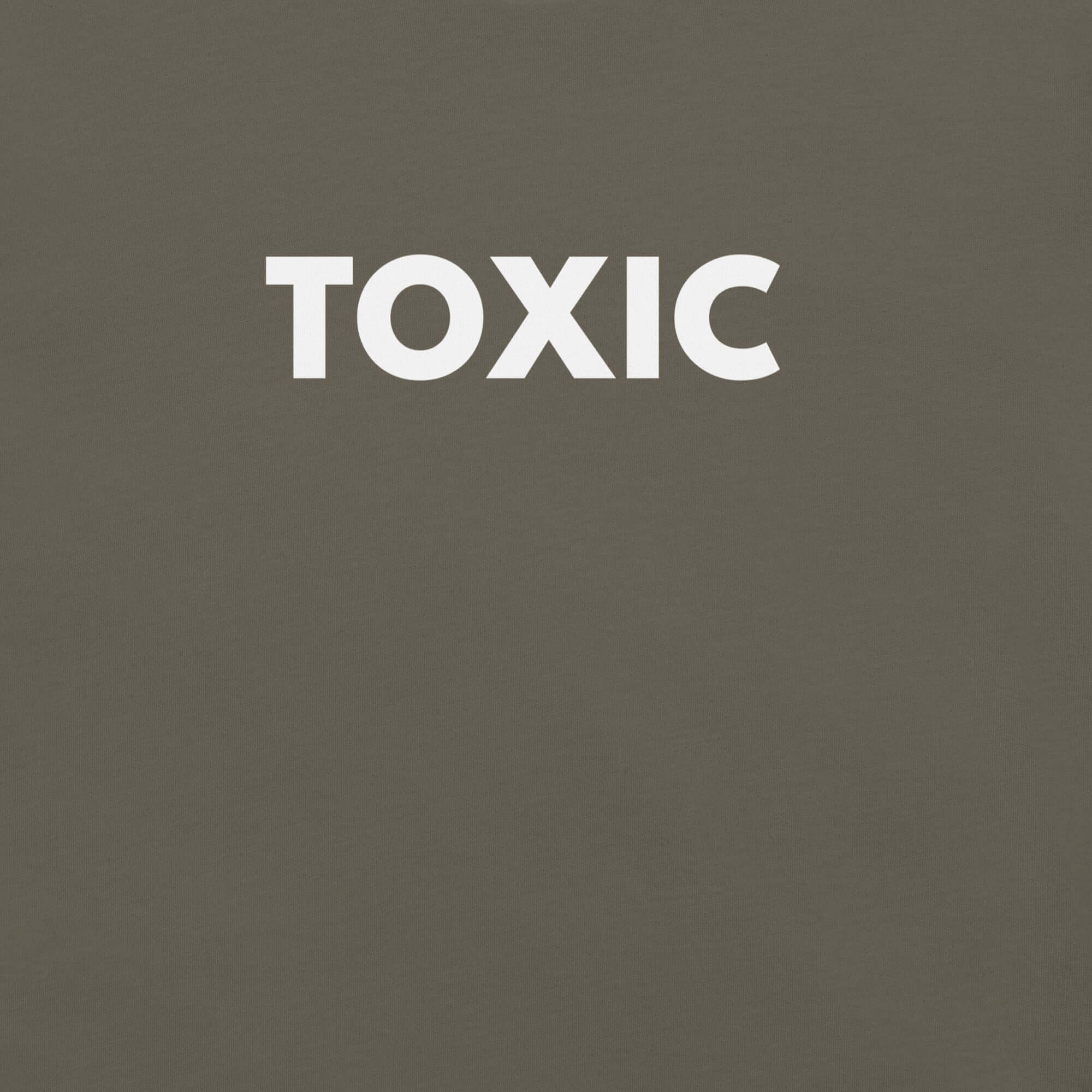 Man wearing army “TOXIC” t-shirt, standing with hands in pockets, looking slightly to the side.