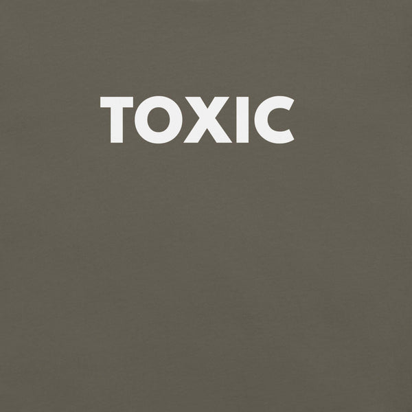 Man wearing army “TOXIC” t-shirt, standing with hands in pockets, looking slightly to the side.