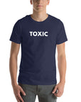 Man wearing navy “TOXIC” t-shirt, standing straight with hands relaxed by pockets, facing forward.
