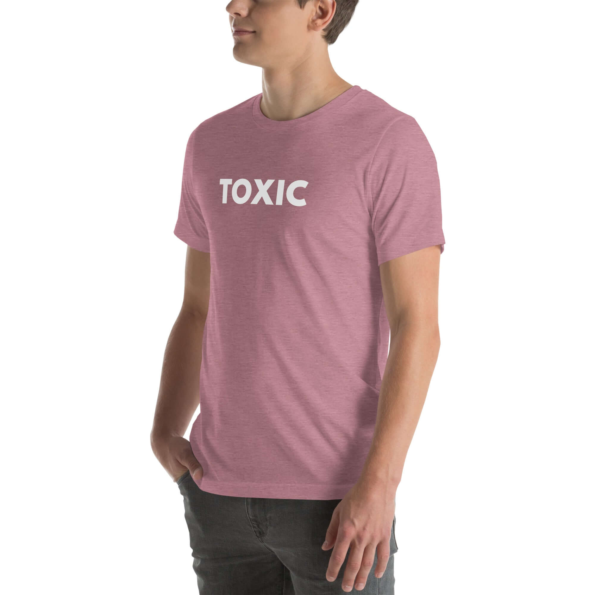 Man wearing orchid “TOXIC” t-shirt, standing sideways with hands in pockets, looking off to the side.