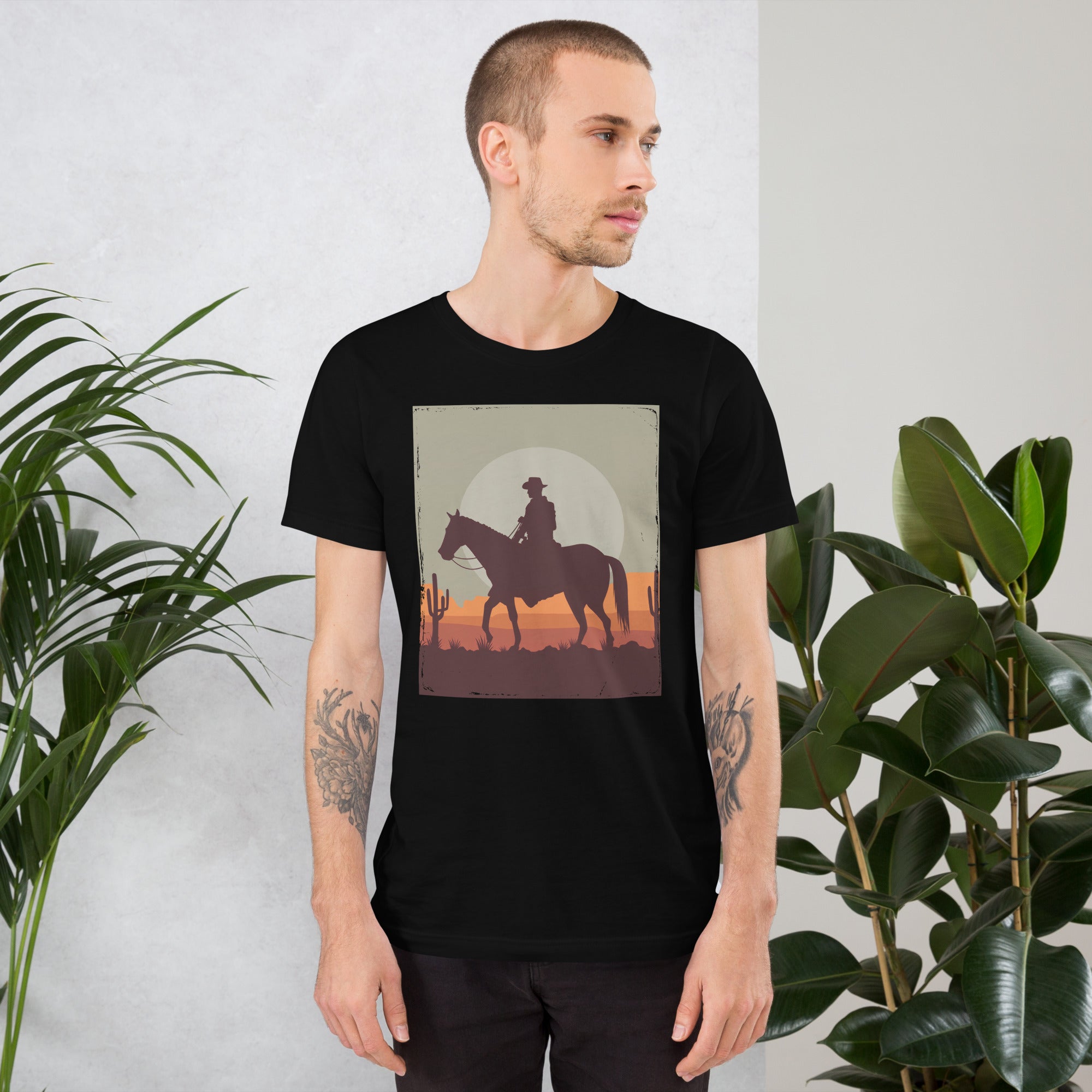 Unisex black t-shirt featuring cowboy silhouette design against desert sunset background, perfect for casual style.