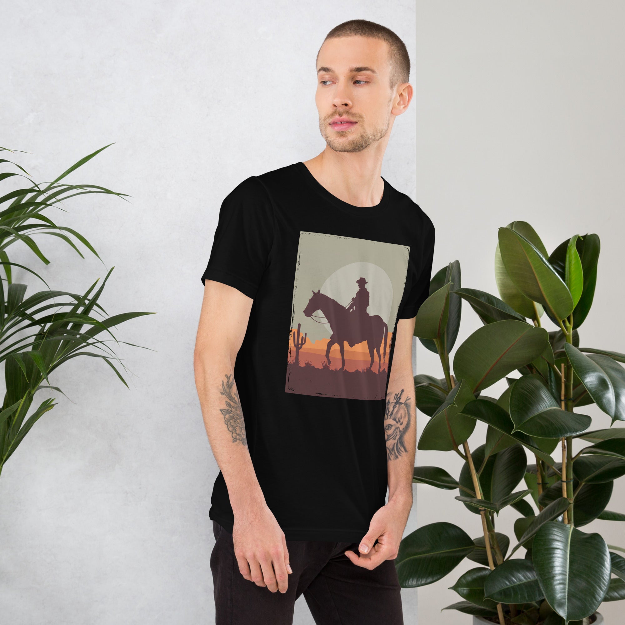 Unisex black t-shirt featuring cowboy silhouette design against a sunset backdrop, perfect for casual wear.