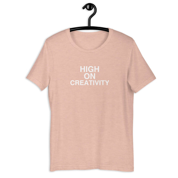Peach t-shirt on a hanger with the phrase “HIGH ON CREATIVITY” printed in white, centered on the chest.
