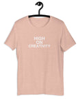Peach t-shirt on a hanger with the phrase “HIGH ON CREATIVITY” printed in white, centered on the chest.